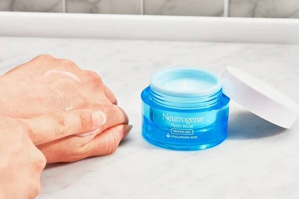 Finger smearing Neutrogena Hydro Boost Water Gel with Hyaluronic Acid on back of hand with nearby container