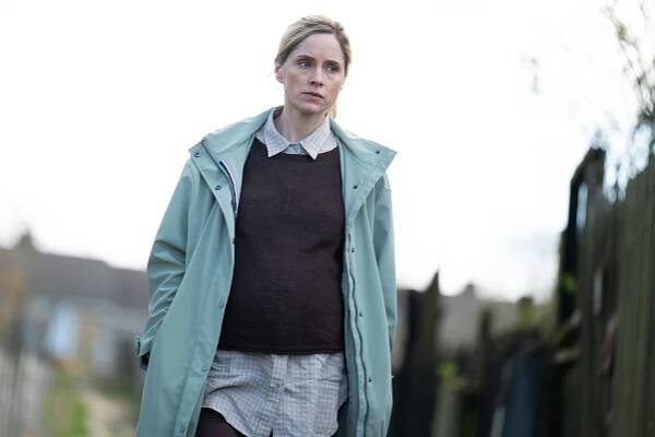 a woman wearing a green coat and a brown sweater