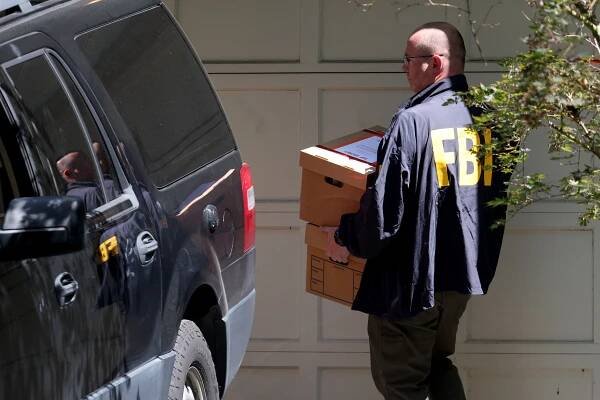 FBI agent carrying boxes from John Bolton's home.