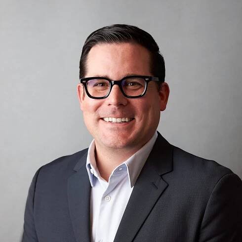 Smiling man in suit and glasses.