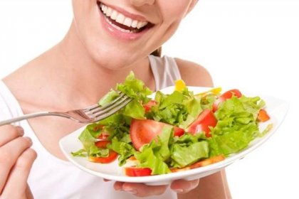 smiling young woman eats salad