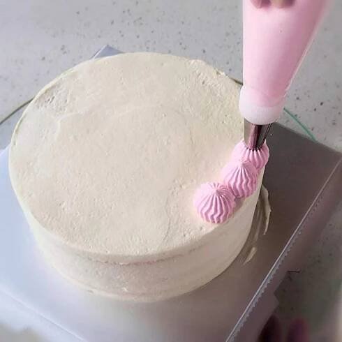 a cake being frosted with pink icing