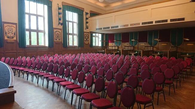 Řady židlí připravené pro konferenci nebo školení ve společenském sále Beseda