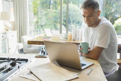 muž pijící kávu a pracující na notebooku v kuchyni - work from home - stock snímky, obrázky a fotky