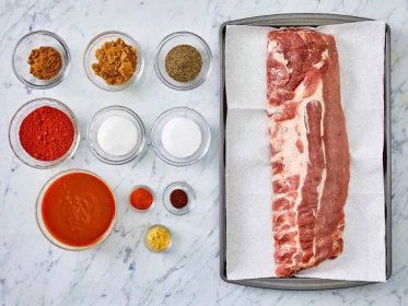all ingredients gathered in various bowls and rack of ribs on a baking sheet