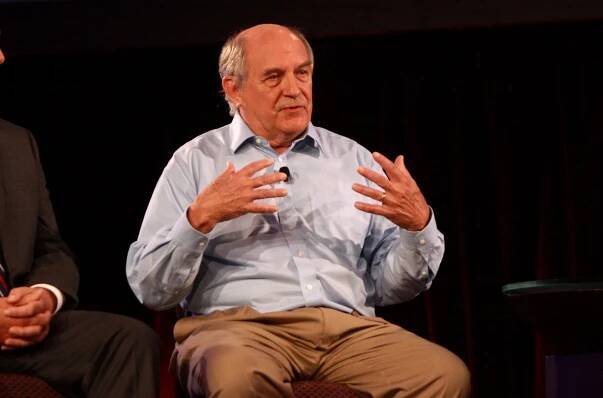 Bald white man speaking on a panel onstage