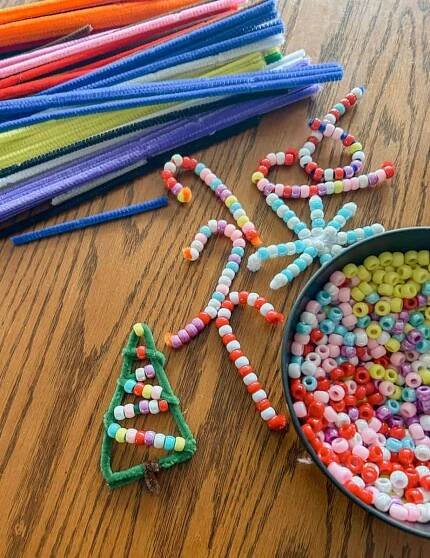 pipe cleaner candy canes, snow flake and christmas tree on table with beads and pipe cleaners