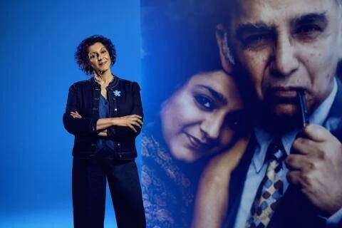 Meera Syal standing in front of a large picture of her father
