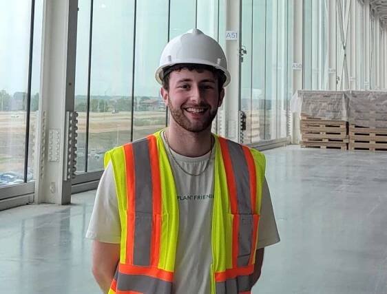 Tyler Hall wearing a safety vest and a hard hat while on a construction site.