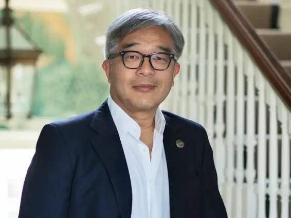 James Chen, wearing a navy jacket and white shirt, stands with one hand on a bannister for a portrait