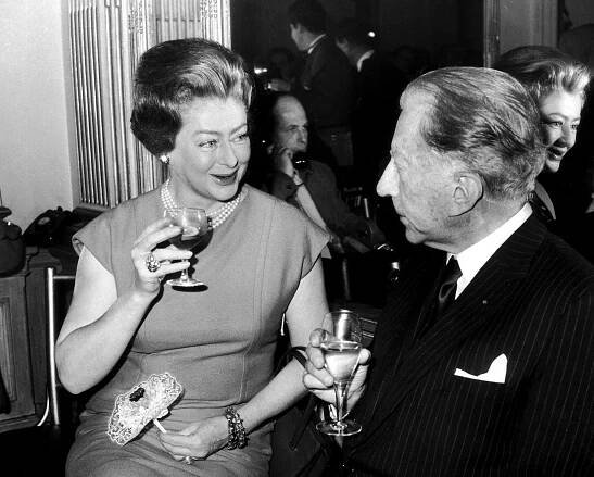 Image may contain Human Person Suit Coat Clothing Overcoat Apparel Joan Crawford Drink and Beverage
