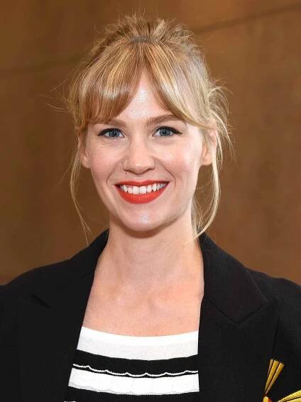 January Jones with her hair pulled back, face framing bangs, blue and white jacket and red lipstick