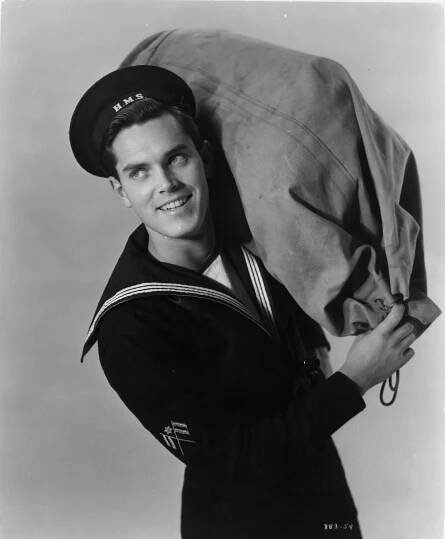 Jeffrey Hunter holding nap sack in publicity portrait for the film 'Sailor Of The King', 1953.