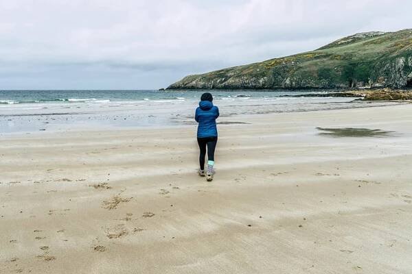 Person am Strand der Church Bay auf der Insel Anglesey