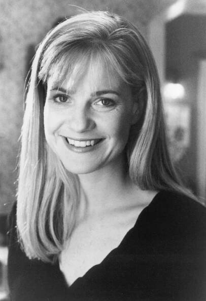 a black and white photo of a woman with long blonde hair smiling at the camera