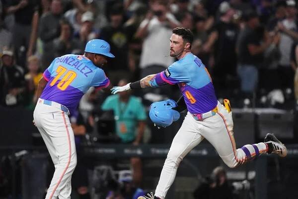Colorado Rockies third base coach Andy González, left, congratulates Brenton Doyle as he circles the bases after hitting a two-run, walkoff home run off Pittsburgh Pirates relief pitcher Dennis Santana in the ninth inning of a baseball game Friday, Aug. 1, 2025, in Denver. (AP Photo/David Zalubowski)