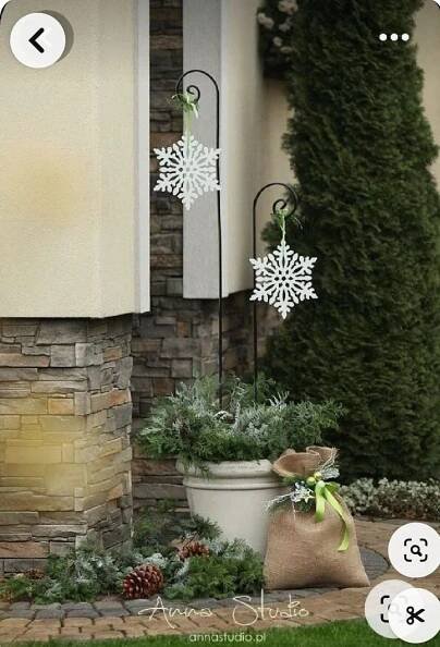 a snowflake hanging from the side of a house next to a potted plant