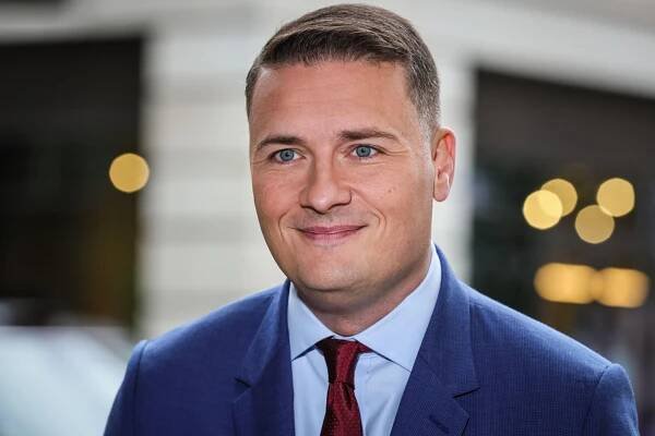 a man in a suit and tie smiles for the camera