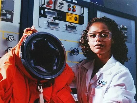A woman holds up an orange spacesuit