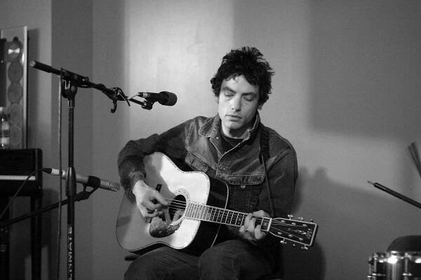 Jakob Dylan strumming guitar during a live performance for Kink 101.9 fm