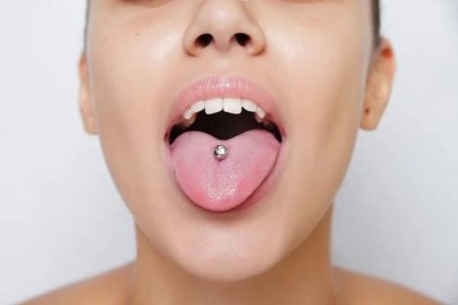 Krásná žena, trčí jí jazyk a ukazovat mladým piercing — Stock obrázek