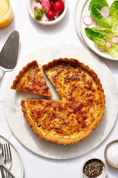 the whole quiche Lorraine being sliced to serve.