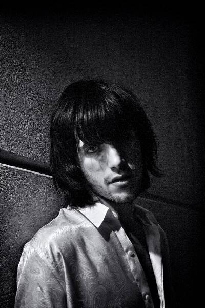 Young man portraited against a wall with a single light beam from his right. Milan portrait photographer.