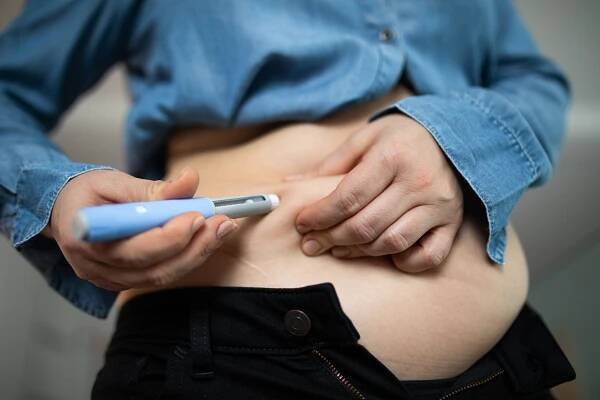 Close-up of a person self-administering a semaglutide injection.
