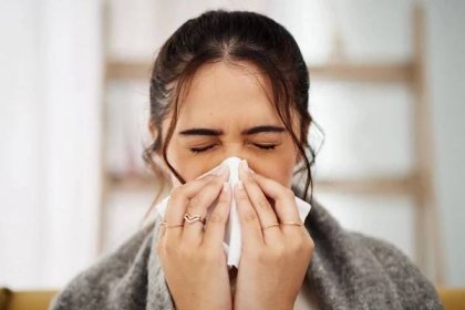 Tissue, nose and sick woman sneezing in living room with allergy, cold or flu in her home. Hay fever, sinusitis and female with viral infection, risk or health crisis in lounge with congestion
