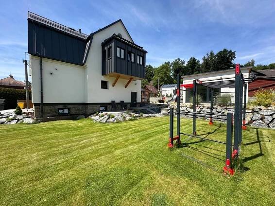 a house with a black roof and a grass yard at Vila Kosmonautka - Velké Losiny in Velké Losiny