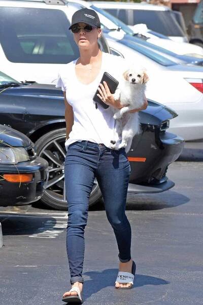 Kaley Cuoco keeps fights the heat as she wears a cap and carries her dog on a hot summer day in Los Angeles.