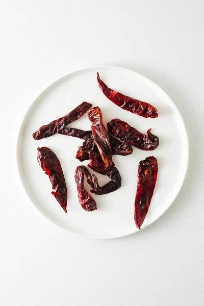 Dried cayenne chilli peppers on a white plate viewed from above.