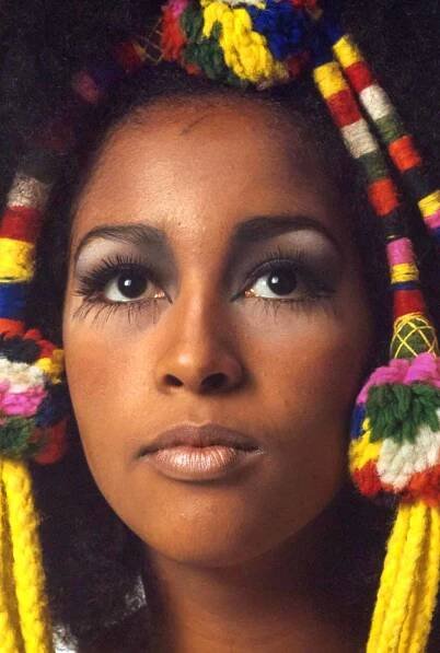 Actor Marsha Hunt in a studio with multicolored woven yarn and pom-pom decorations in her hair