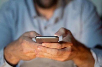 Zblízka teenager nebo dospělý muž hrát online a odesílání textu na smartphonu s barevné pozadí světla z obrazovky v závislost na mobilní hraní připojení k Internetu a nové technologie. — Stock obrázek