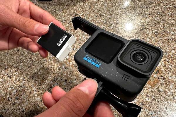 A person places the battery pack into the GoPro HERO12 Camera