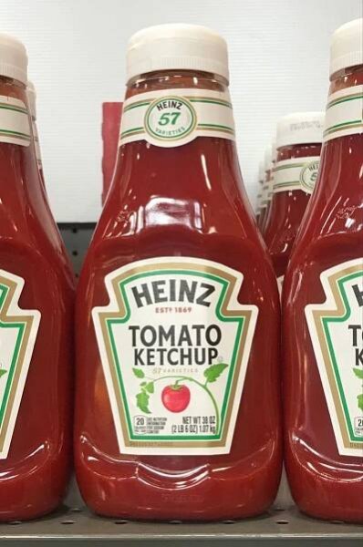 bottles of heinzz tomato ketchup sit on a shelf