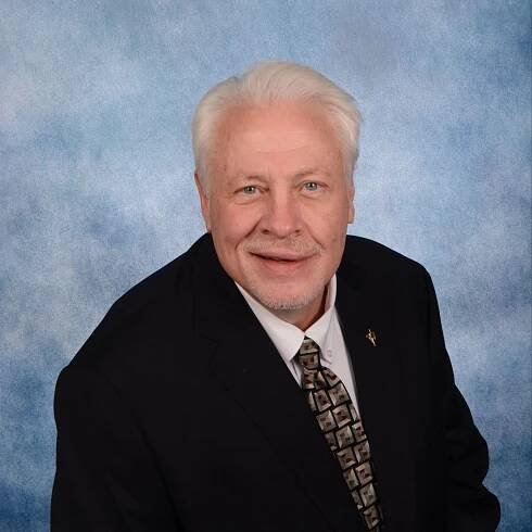 A man in a suit and tie is smiling for the camera