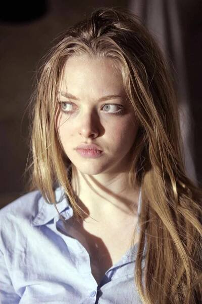 a woman with long blonde hair wearing a blue shirt and looking off to the side