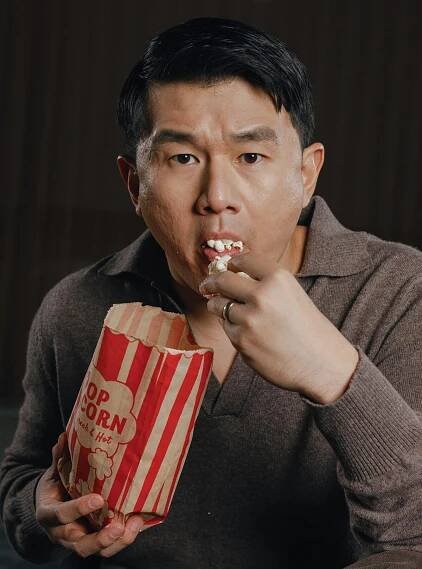 Man in a brown shirt eating popcorn