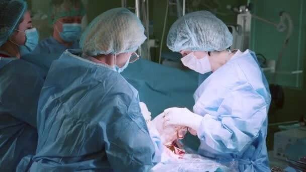 Dítě se narodilo v císařské sekci. Skupina doktorů v masce a čepicích sklonila hlavu nad pacientem. Doktoři provedou operaci císařského řezu. Doktor a sestra rodí novorozeně — Stock záběr