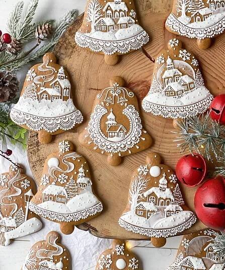 gingerbread cookies decorated with white icing on a wooden platter next to christmas decorations