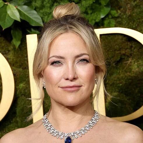 Kate Hudson in an elegant event setting, wearing a necklace and styled hair