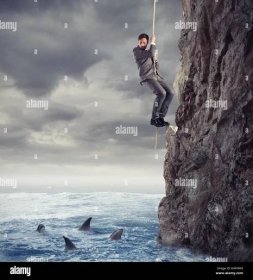 Businessman is likely to fall into the sea with sharks. concept of problems and difficulty in business Stock Photo