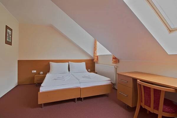 a small room with a bed and a desk at Hotel České Žleby in Stožec