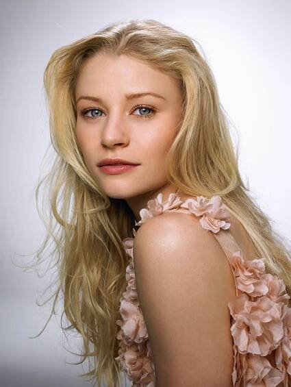 a woman with long blonde hair is posing for a photo in front of a white background