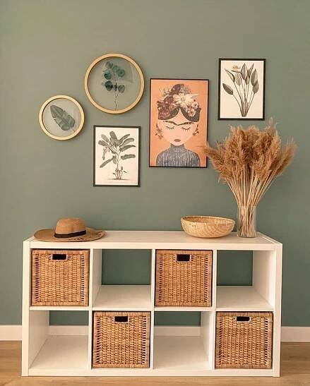 a white shelf with baskets and pictures on the wall
