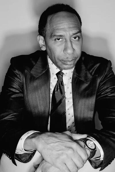 Stephen A. Smith, in a blazer and tie, poses for a photo.