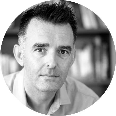A black and white photo of a man with short dark hair posing for a headshot photo.