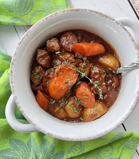 white bowl of Dutch Oven Irish Stew on a green cloth.
