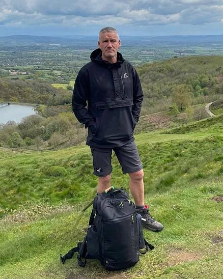 a man standing on top of a hill with his hands in his pockets